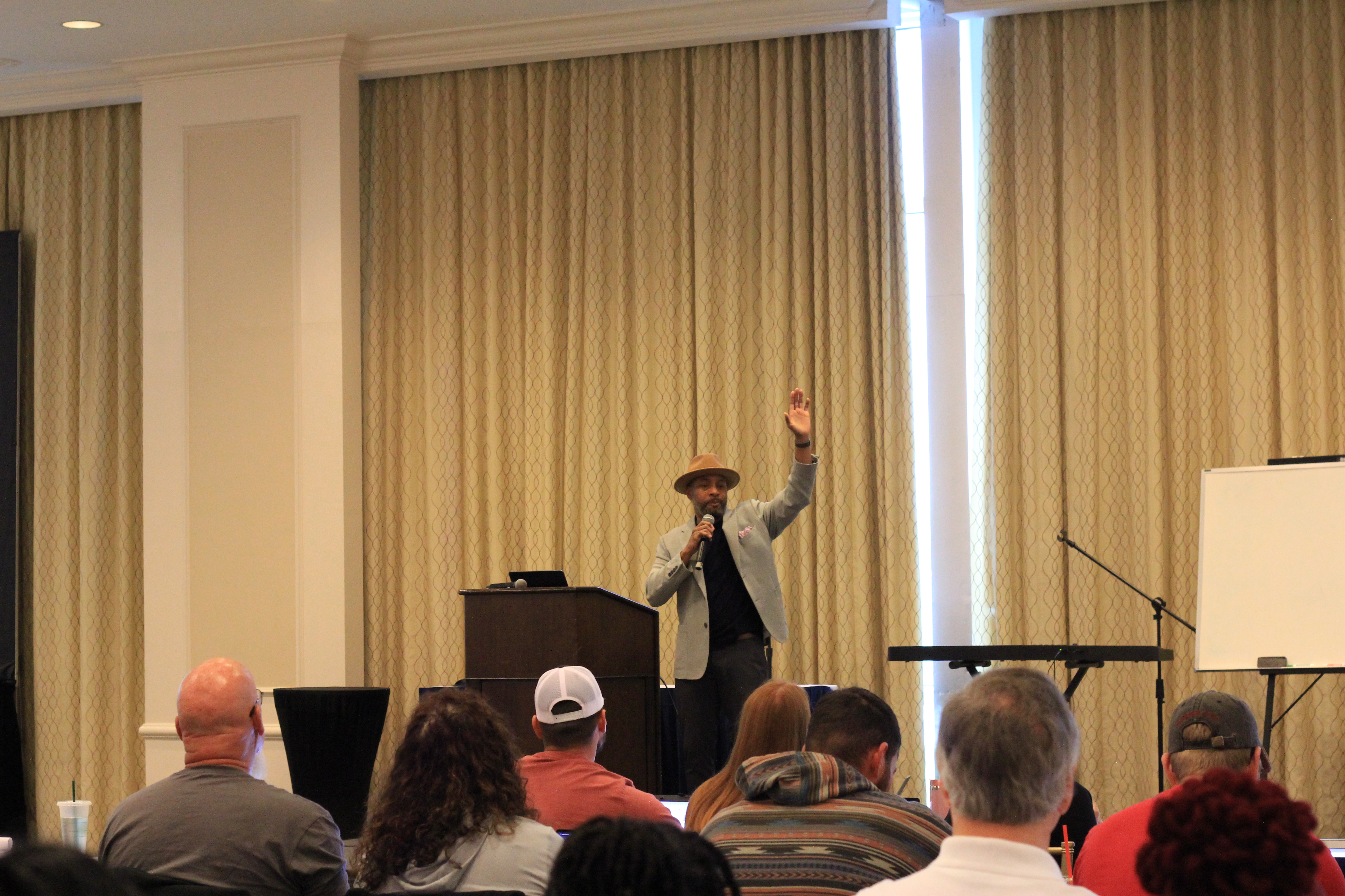 Coach Brian King commanding the room at a Trade Momentum live event — full house, live charts, real results